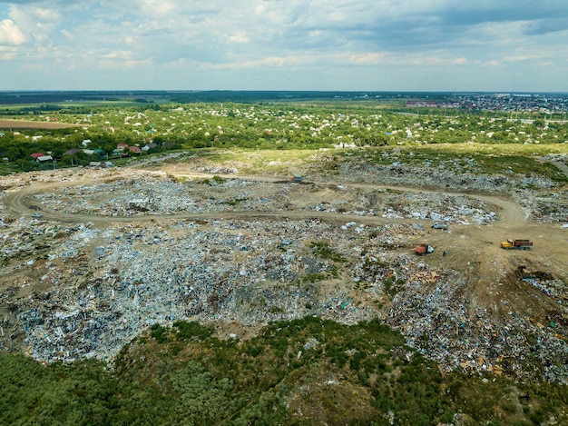 A wide shot of a landfill in Brazil, overflowing with plastic waste. Birds fly overhead as scavengers pick through the debris. A sign indicating 