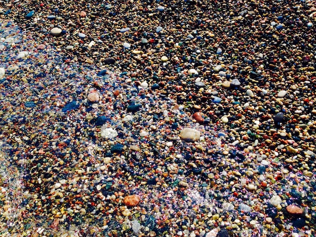 A close-up shot of microplastics accumulating on a beach in Brazil. The sand is mixed with tiny fragments of colorful plastic, highlighting the pollution problem.