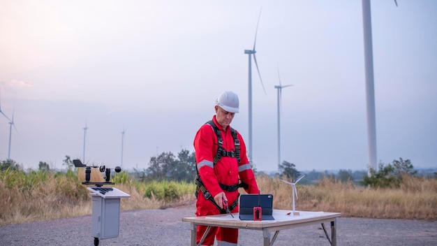 Photo of a user holding a multimeter testing a small homemade wind turbine. The background shows a garage with various tools and equipment. The focus is on the turbine and the user interacting with it.