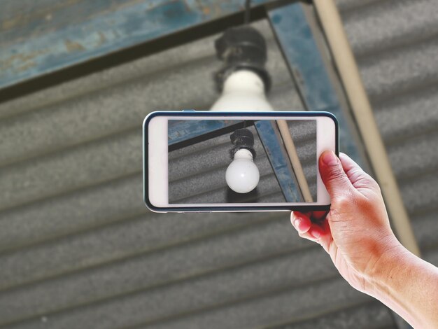 A close-up of a smartphone displaying a security camera app interface. The screen shows a live feed from one of the security cameras, with options visible for recording, adjusting settings, and viewing past footage. The app is clean and user-friendly.