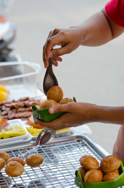 A close-up of a woman expertly preparing acarajé on a street food stall, surrounded by the vibrant colors of the ingredients and the bustling energy of the market. She wears traditional Bahian clothing, and her movements are skilled and practiced. The acarajé are frying in a pan, and there are bowls of vatapá, caruru, and salad arranged around her.