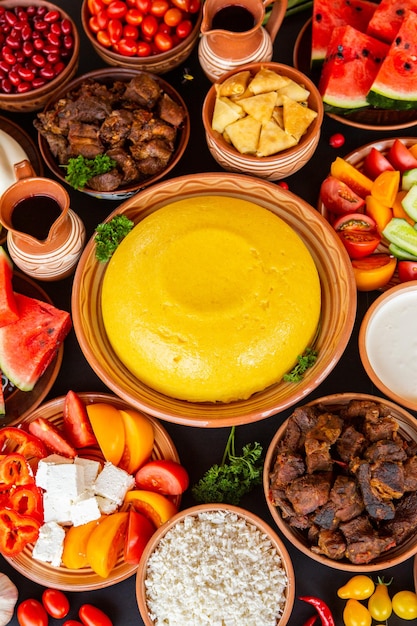Aerial view of several bowls of traditional Brazilian desserts such as cocada and quindim with various colors. The bowls and background are colorful and festive.