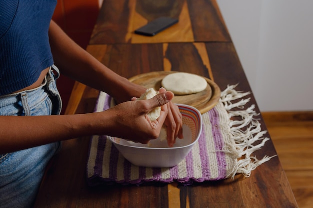 Indigenous women preparing a traditional Brazilian dish with manioc flour, using a wooden mortar and pestle. The scene is set in a rustic kitchen, showing the traditional methods of food preparation and the communal aspect of indigenous cooking.